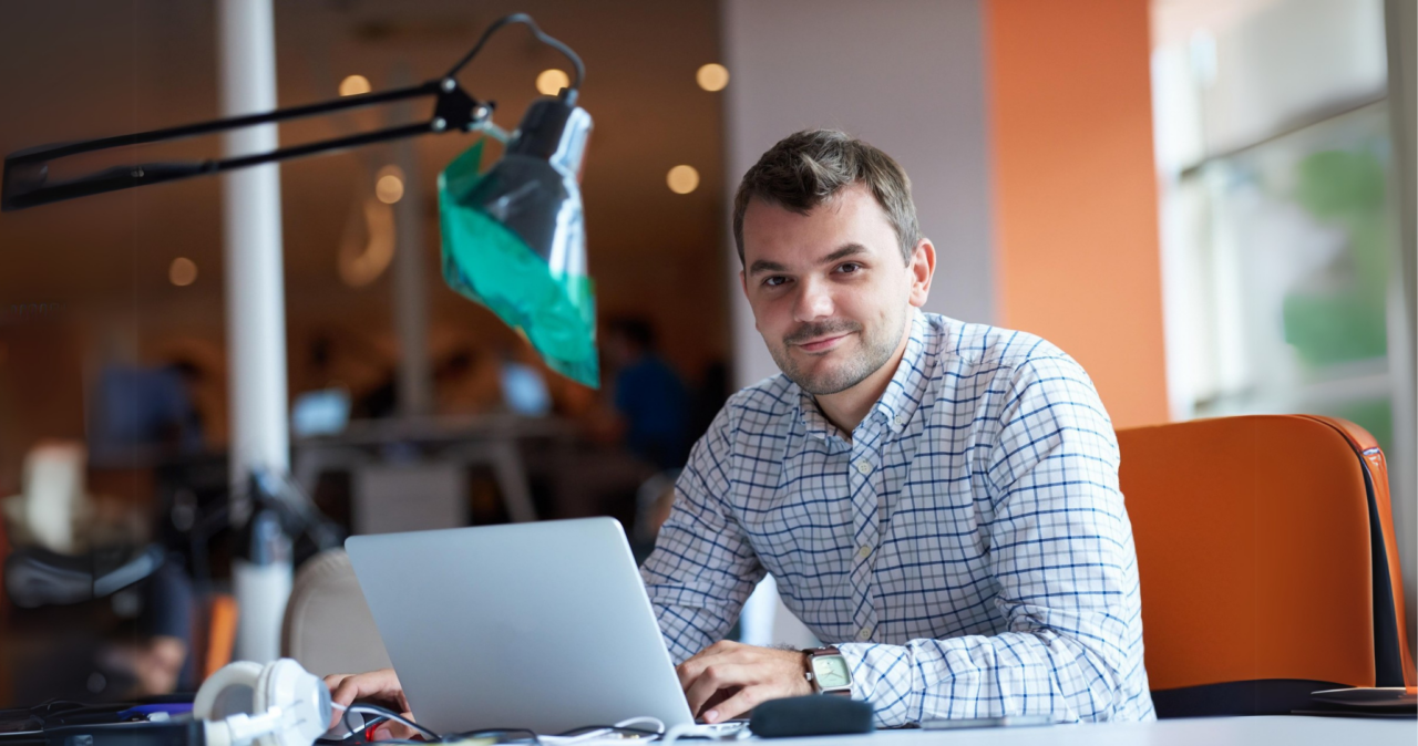 Ein Mann sitzt vor dem Laptop und freut sich über die Maßnahmen der Mitarbeiterbindung in seinem Unternehmen