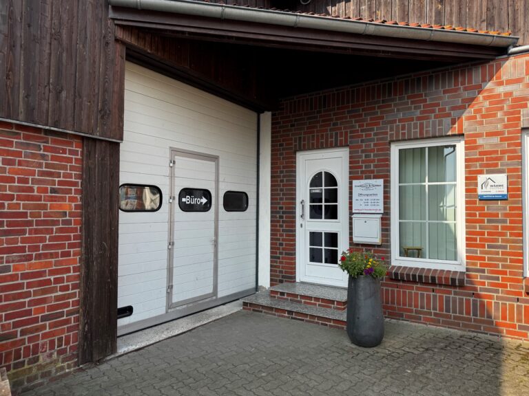 Eingang der Firma Grossmann & Hünken. Ein rotes Backsteinhaus mit einer Eingangstür und einem größeren Garagentor